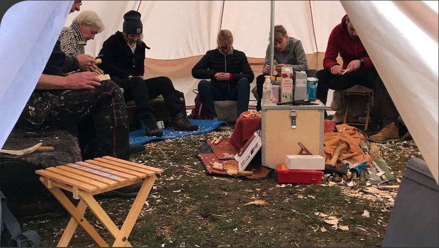 En grupp människor sitter i ett stort tält och täljer tillsammans