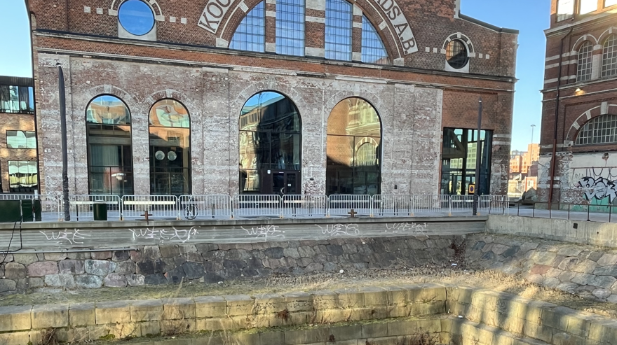 Ett gapande hål i marken syns framför en äldre tegelbyggnad.