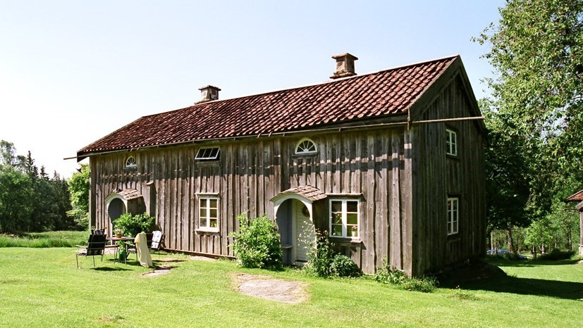 Ett äldre hus med omålad fasad och tegeltäckt sadeltak