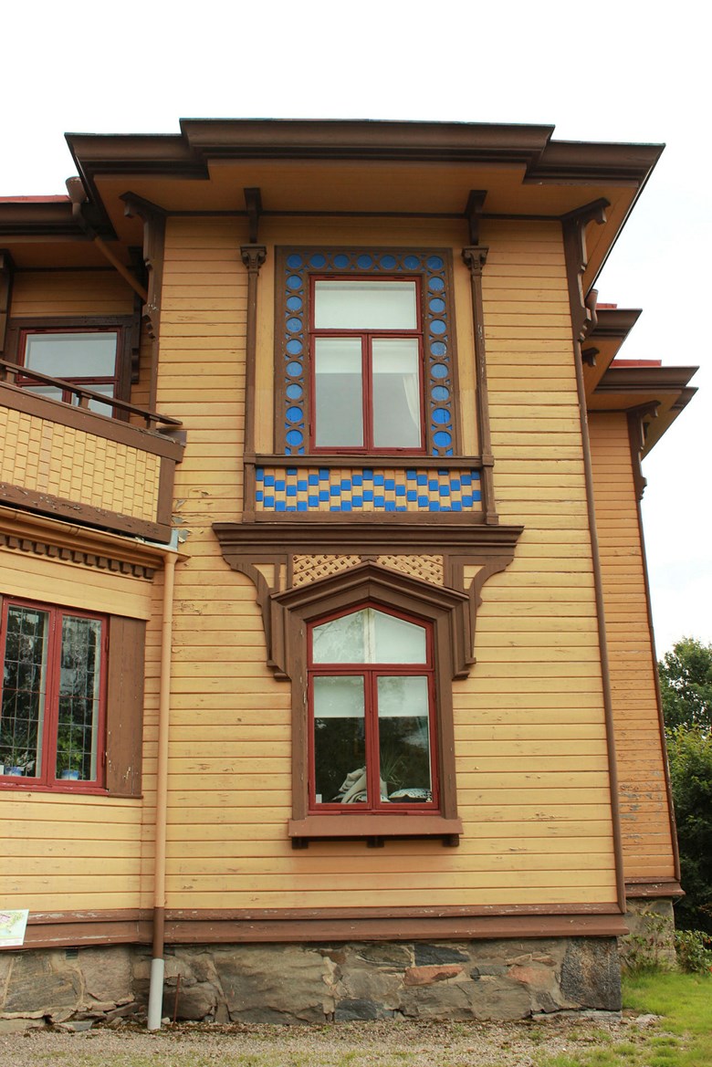 Närbild på fasad med fönster med flera olika detaljer i blått, brunt och rött