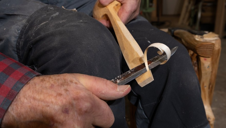 Närbild på två händer som skär i en träbit