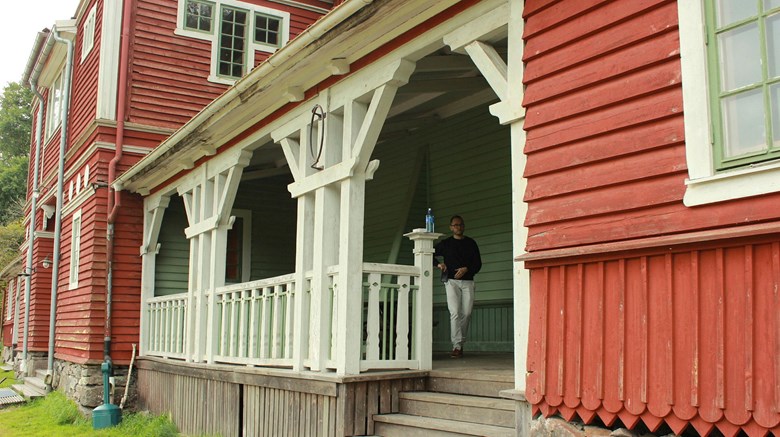 Detalj av rött trähus med vita snickerier på veranda