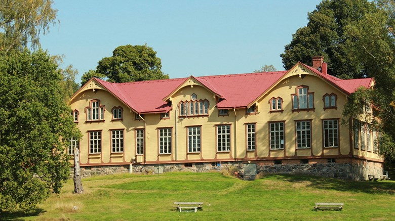 ett stort gult skolhus med rött tak och bruna detaljer