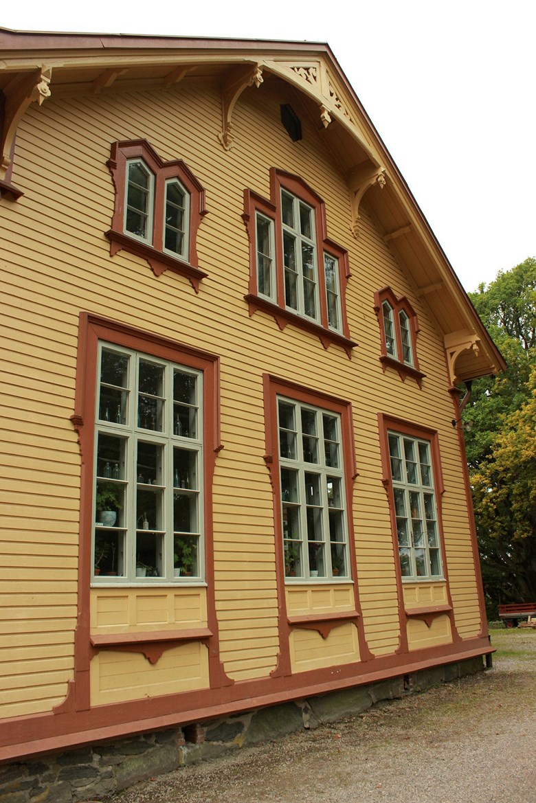 Gaveln på ett stort gult hus med röda foder och ljusgrå fönster