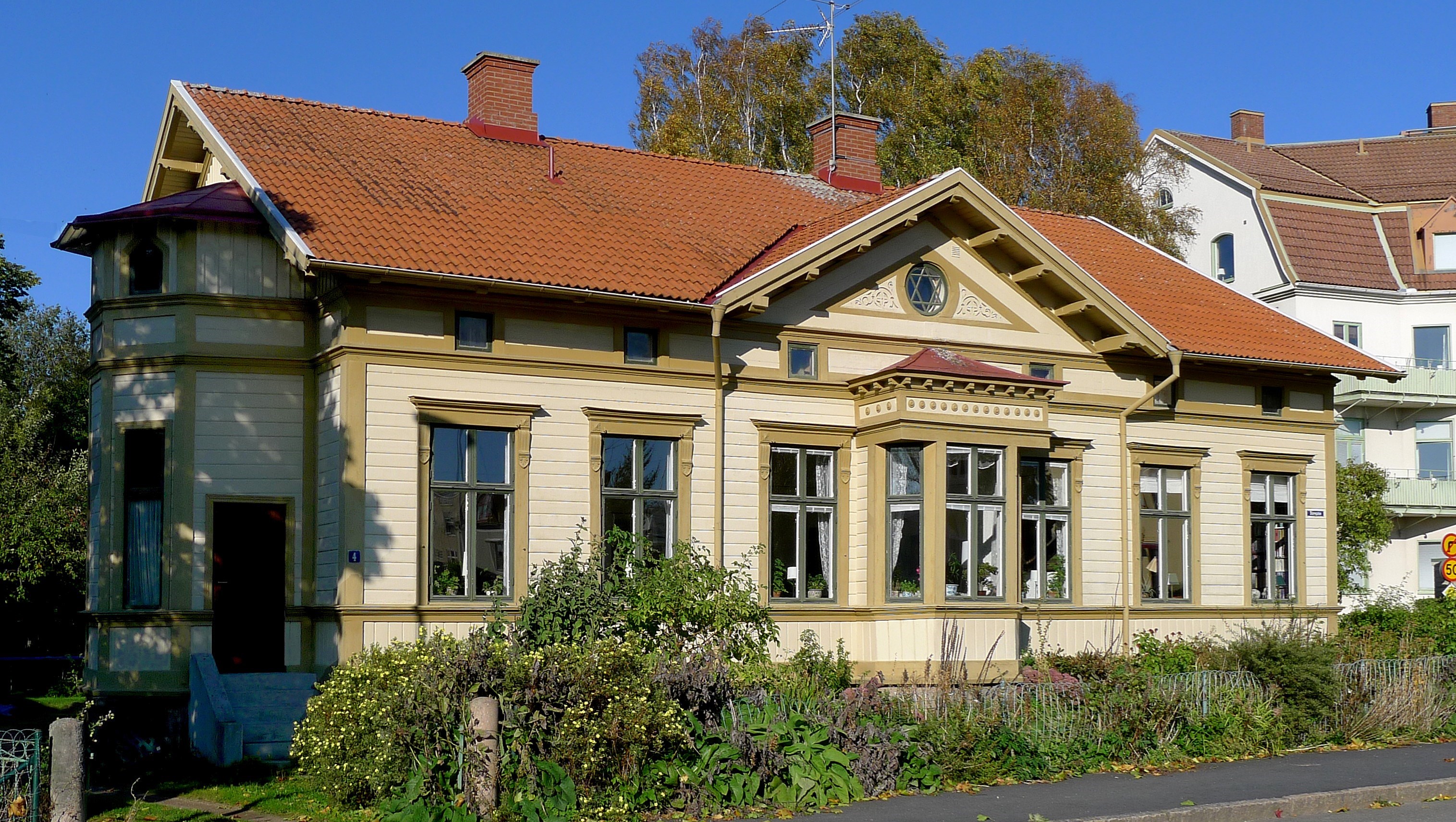 Gult hus med markerade fönsterfoder och rött tak