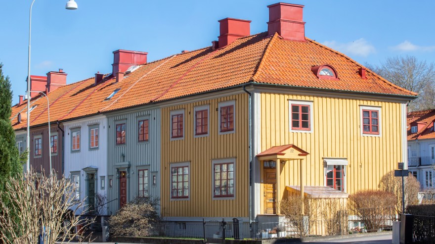 Radhus i trä med flera fasadkulörer och rött tak.