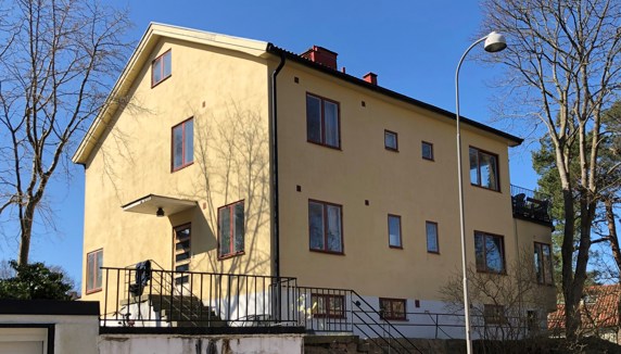 Ett stort putsat tvåfamiljshus från 1930-talet med gul fasad