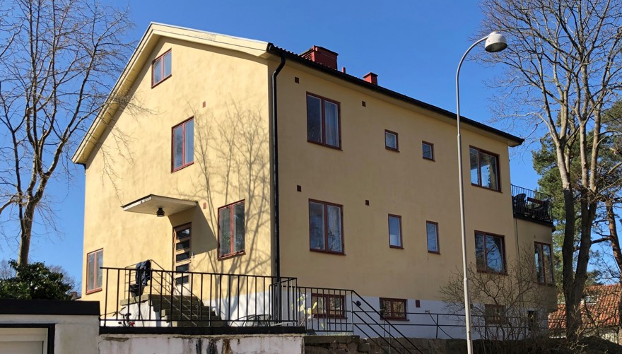 Ett stort putsat tvåfamiljshus från 1930-talet med gul fasad