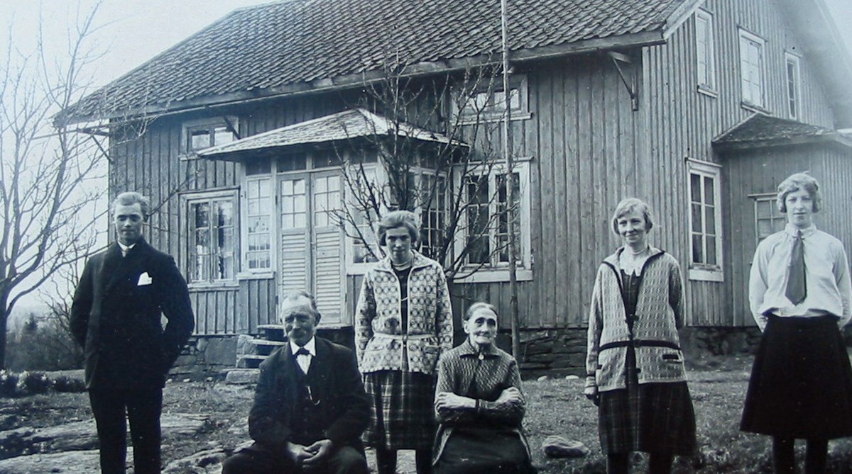 sex personer står framför ett litet trähus med glasveranda