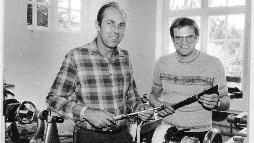 Svartvit bild på två män vid en svarv hållandes verktyg