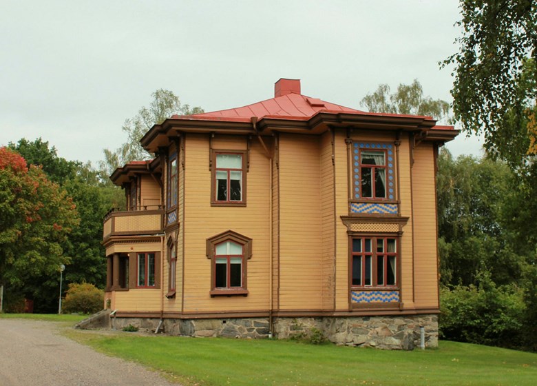 Huset sett från sidan med gul fasad och stensockel