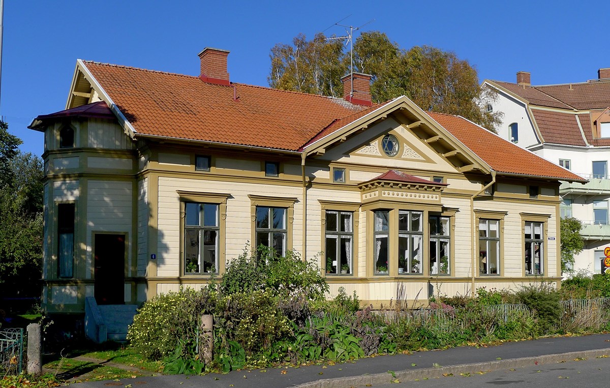 Gul villa med rött tak, bruna snickerier och gröna fönster