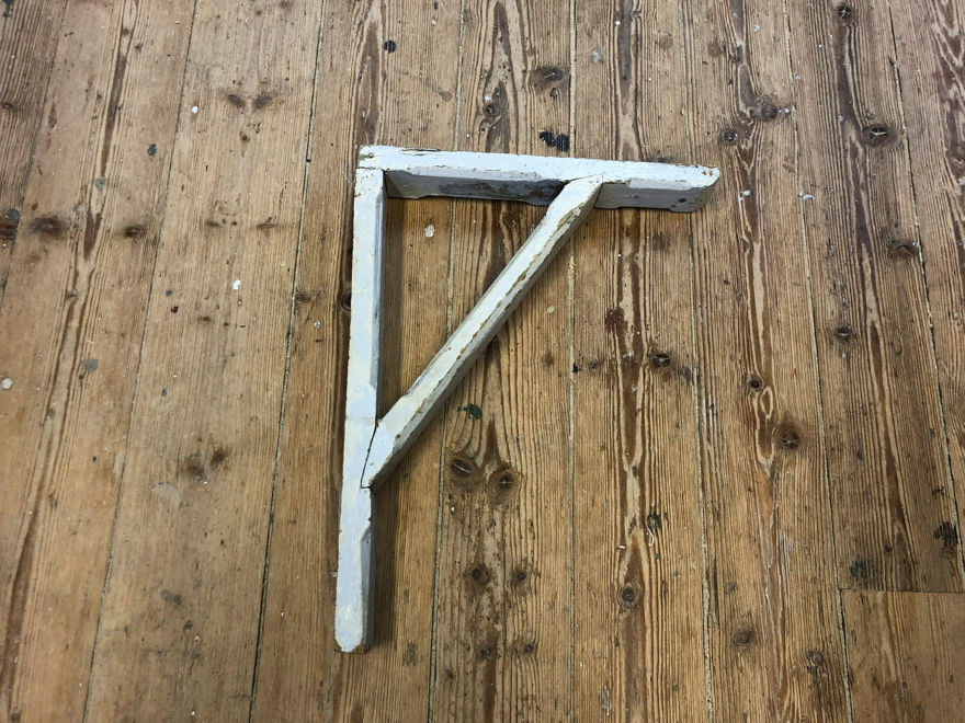 Äldre typ av träkonsol med sliten vit yta