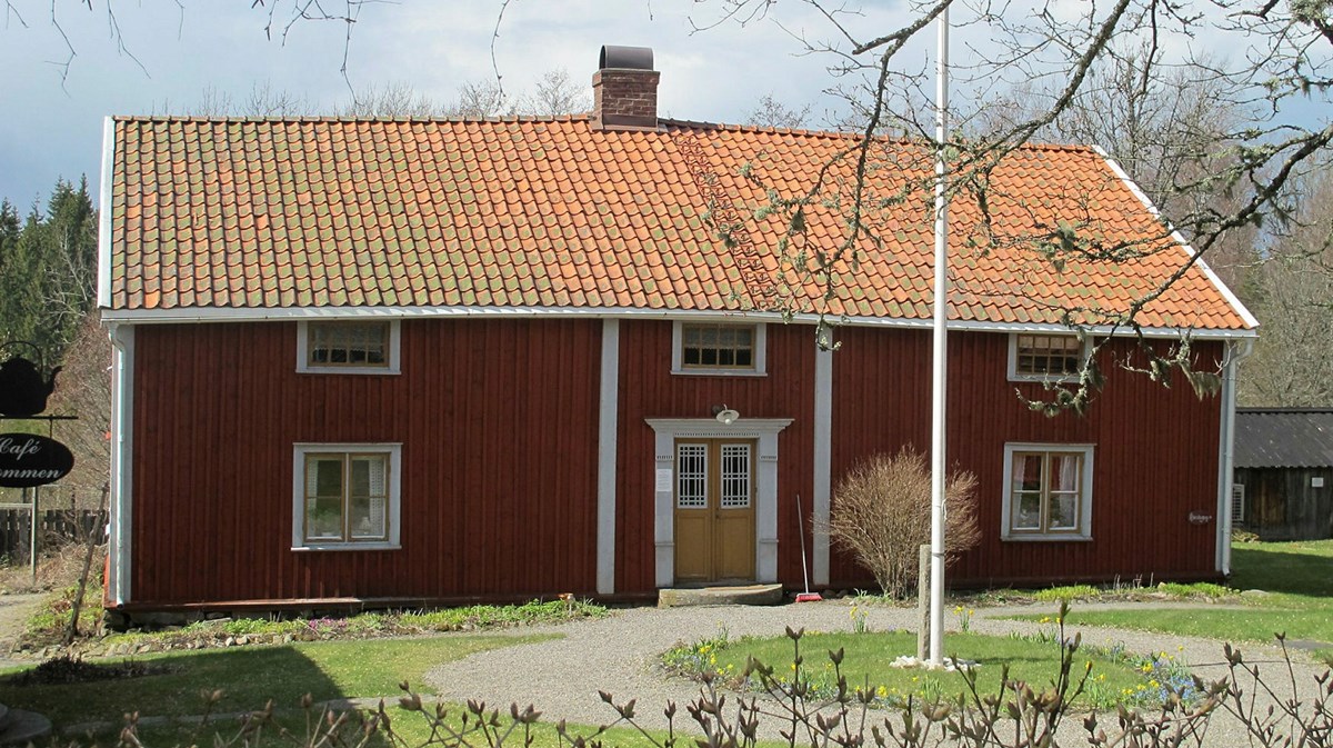 Ett litet rött hus med vita knutar och gul dörr