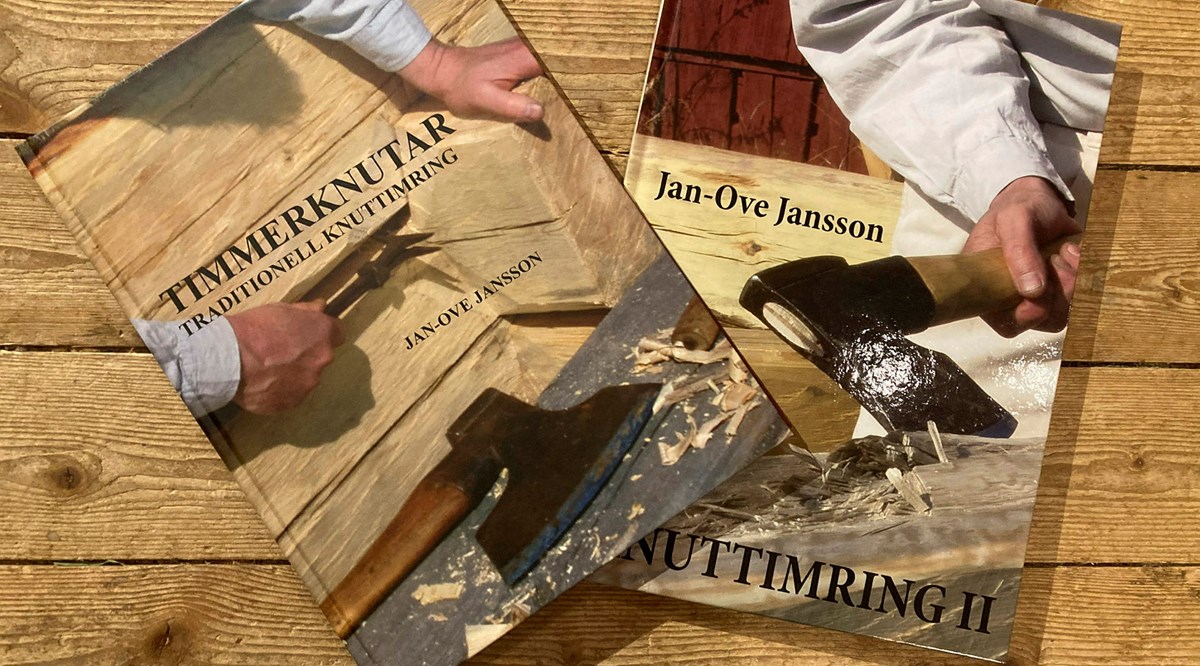 Två böcker om timring ligger på ett slitet trägolv