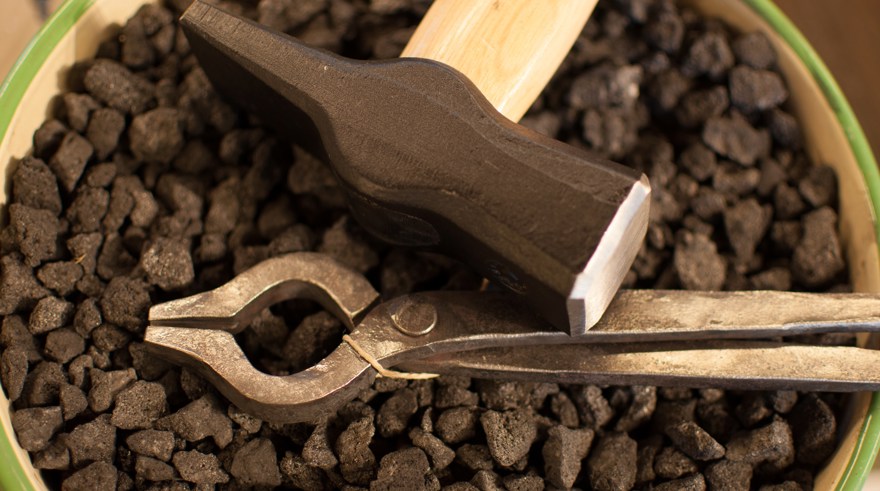 Hammare och tång som ligger på en hink med koks