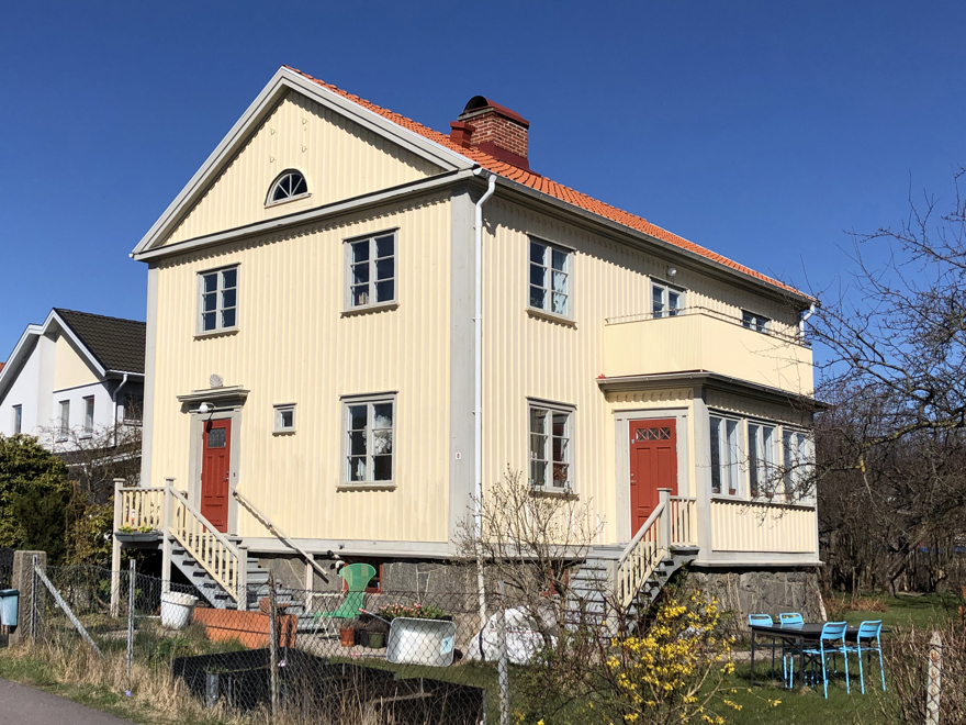 En stor gul villa med grå knutar och röda dörrar.