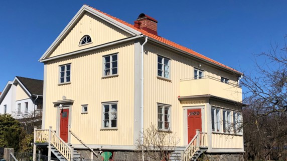 Ett stort gult trähus med grå och röda detaljer