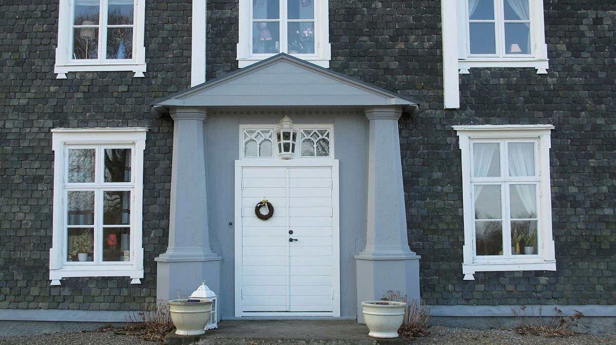 fasaden på ett stort grått hus med fasad av skifferstenar