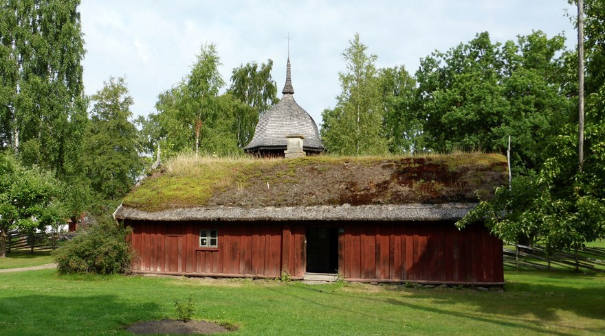 Ett lågt rött trähus med torvtak