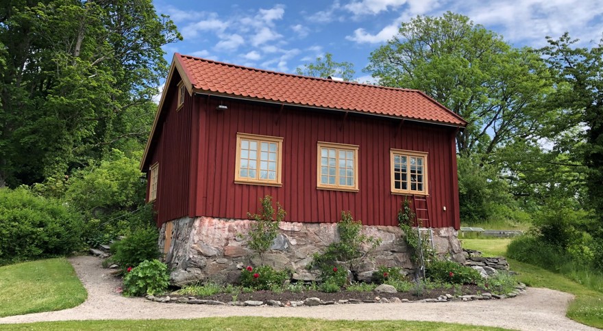 ett litet rödfärgat hus med gula foder och bågar