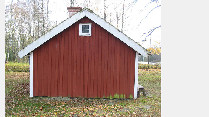 En rödmålad husgavel på en låg byggnad med sadeltak där panelbrädorna är ömsom bredare i botten än vad de är i toppen och ömsom bredare i toppen än i botten.