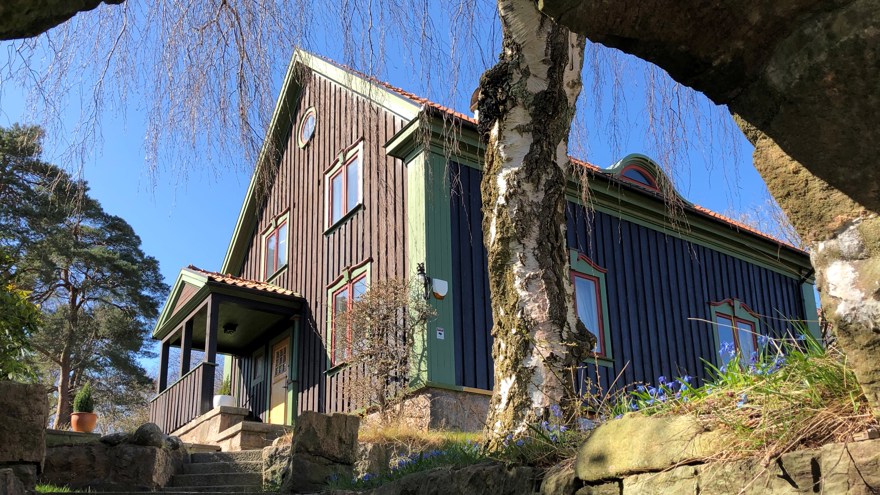 Ett brunt hus med gröna och röda detaljer, sett snett nedifrån