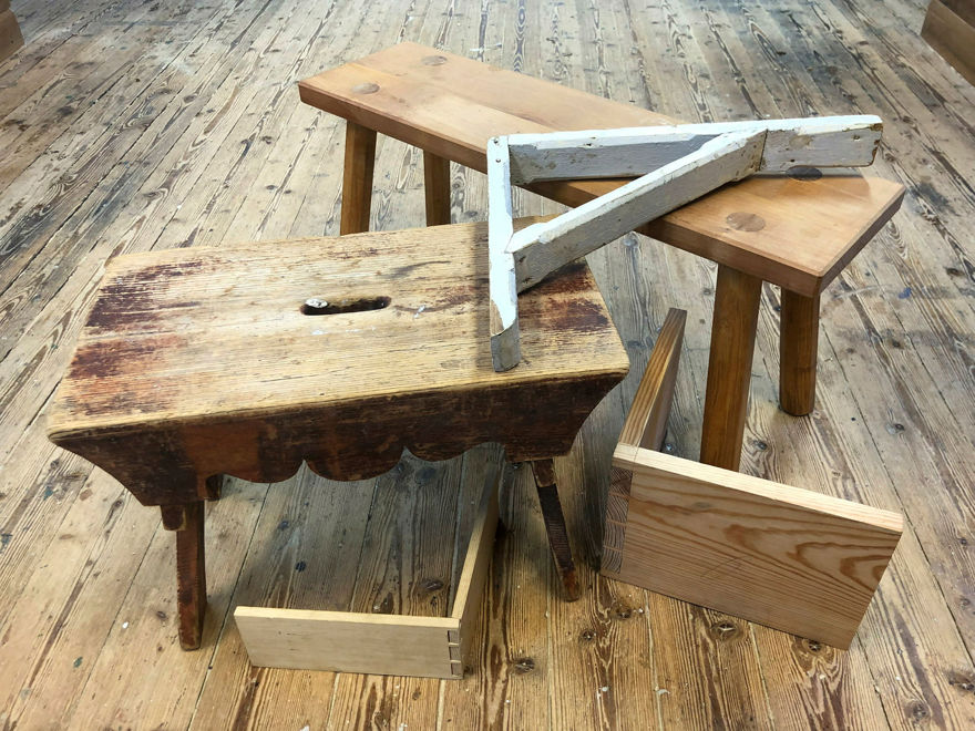 två pallar, en konsol och två delar av trälådor står på ett slitet trägolv