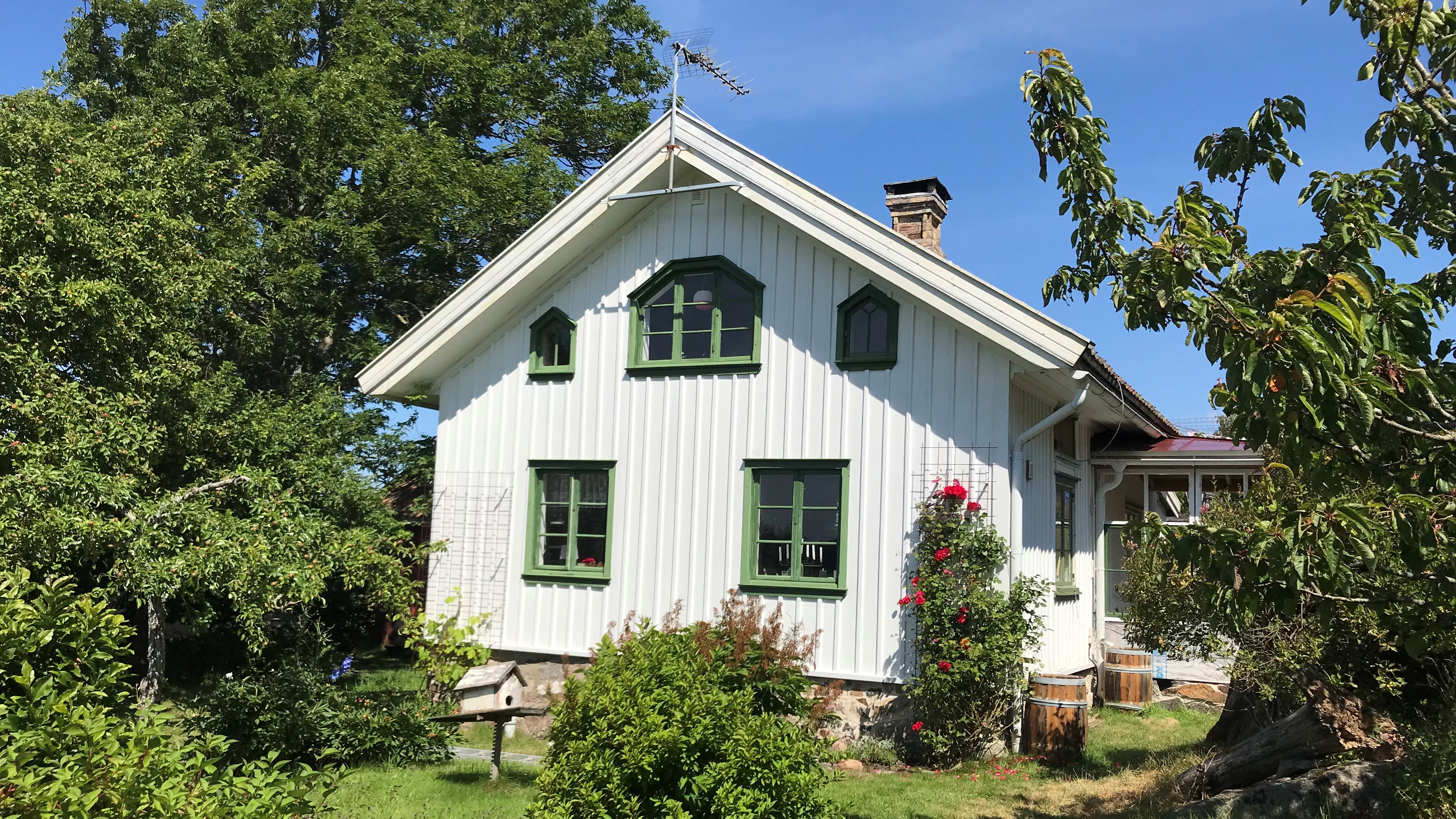 Ett vitt hus med gröna fönster