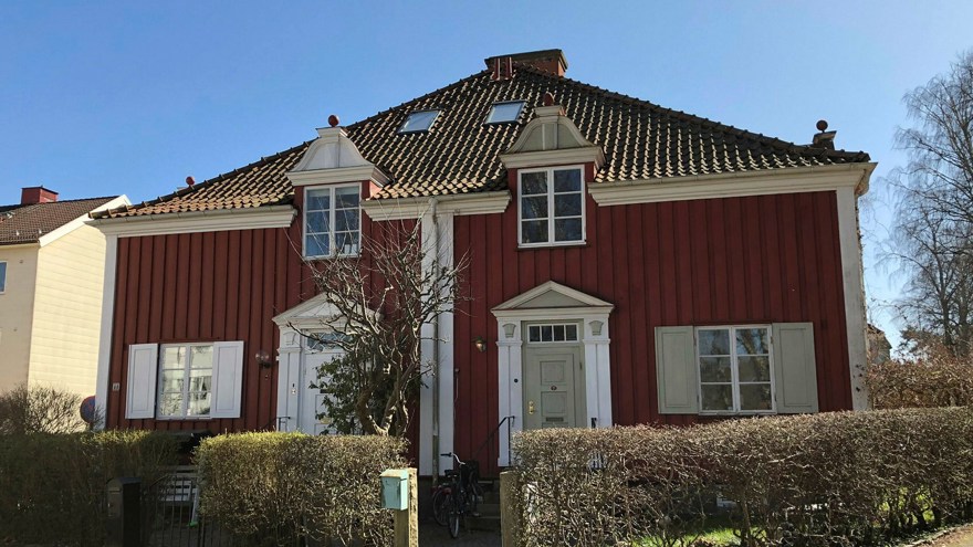 Ett rött parhus med ljusa knutar och brant tegeltak