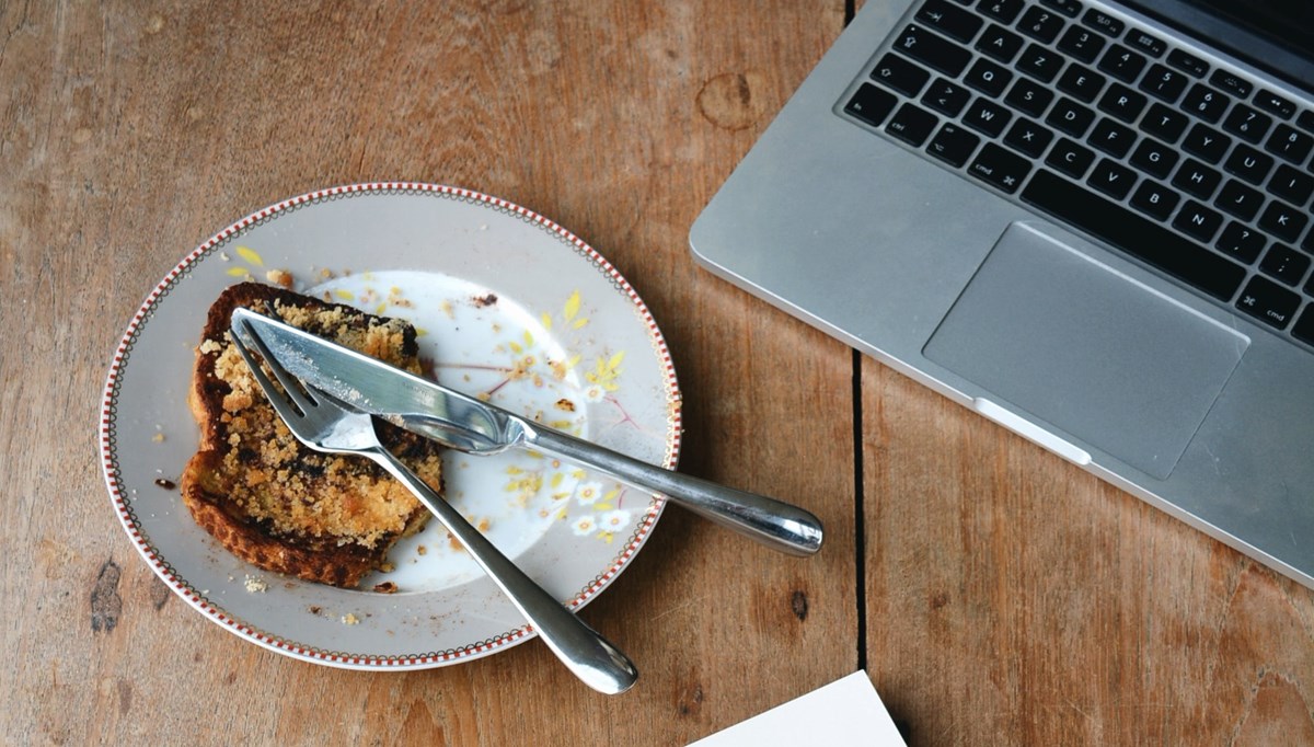 laptop och tallrik med smörgås på träbord