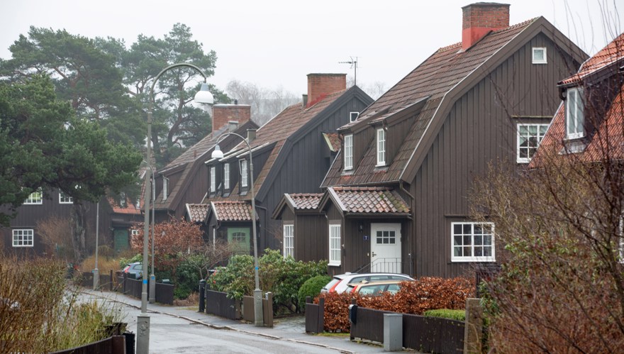 Stora bruna trävillor med vita fönster utmed en smal gata.