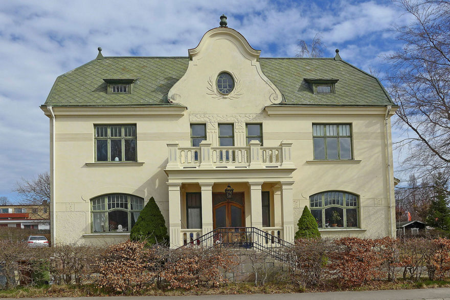 Ett stort ljust putsat hus med gönt tak och pampig entré.