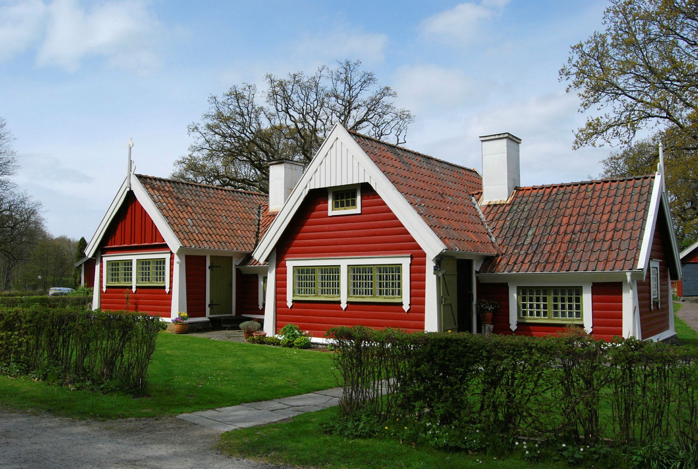 Ett rött envåningshus med vita knutar och gröna småspröjsade fönster.