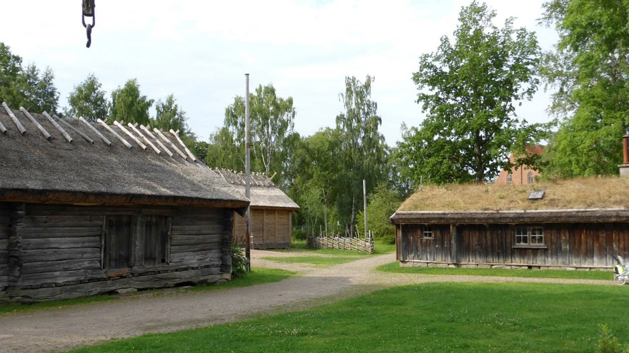 Tre hus i trä med vasstak och omålade fasader