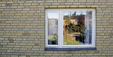 Detalj av fönsterparti i gul tegelvägg. Fönstret  består av ett bredare och ett smalare fönsterluft. Det smalare ska fungera som vädringsfönster.