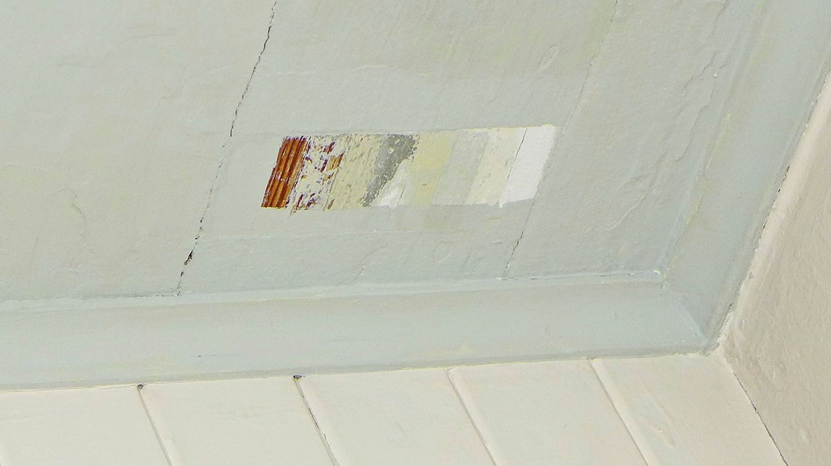 En så kallad färgtrappa där olika färgskikt skrapats fram på ett målat innertak