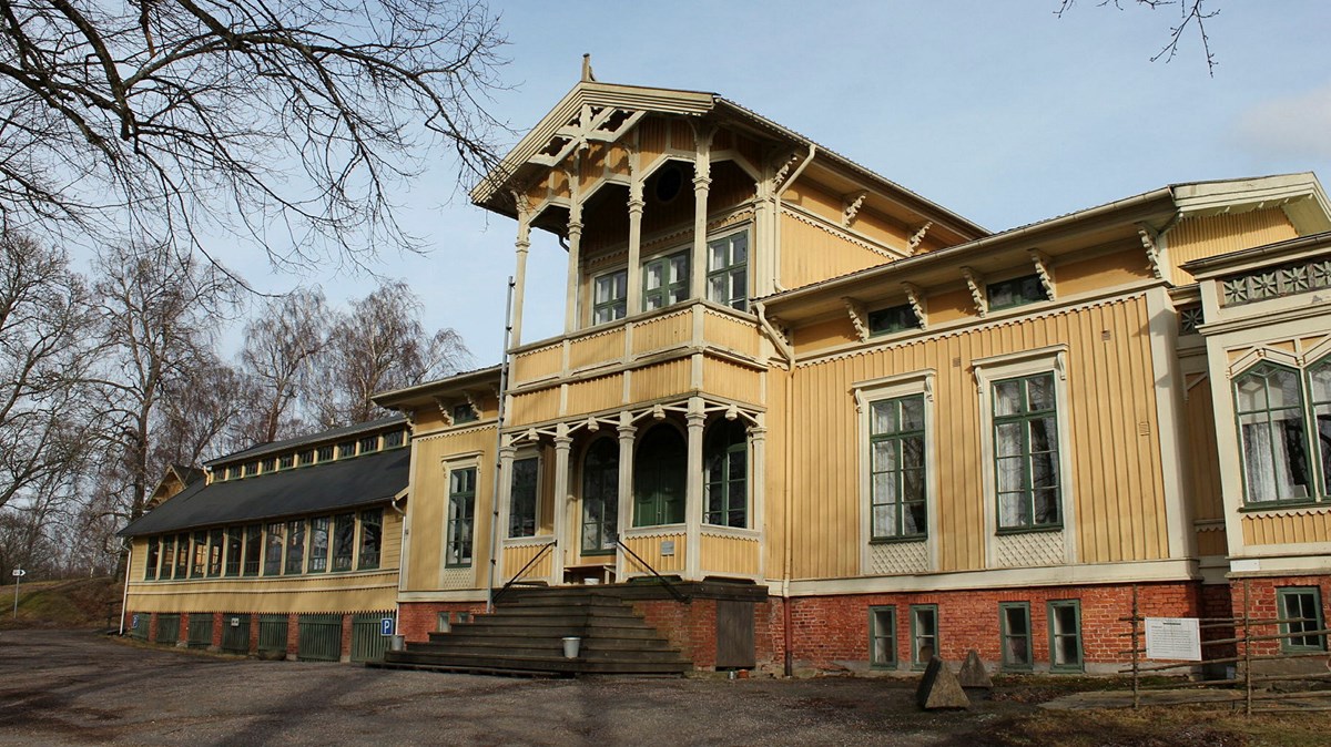 Ett stort gult hus med verandor i två våningar och snickarglädje