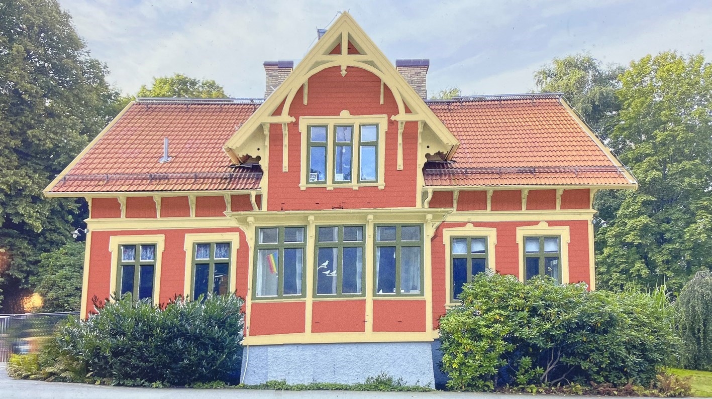 Ett färgglatt hus med röd panel, gula foder och gröna fönster.