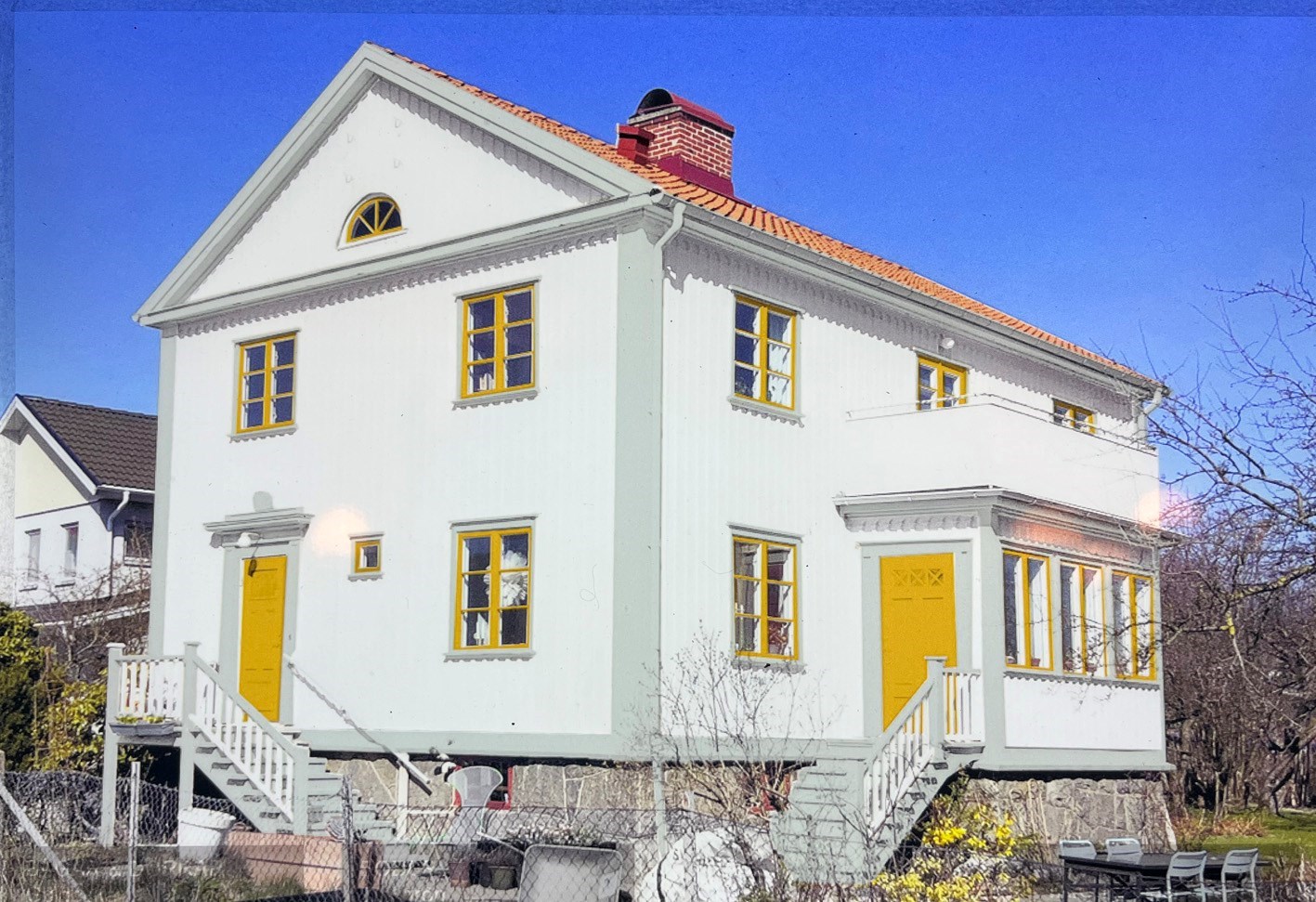 Vitt hus med gula fönster och grågröna foder