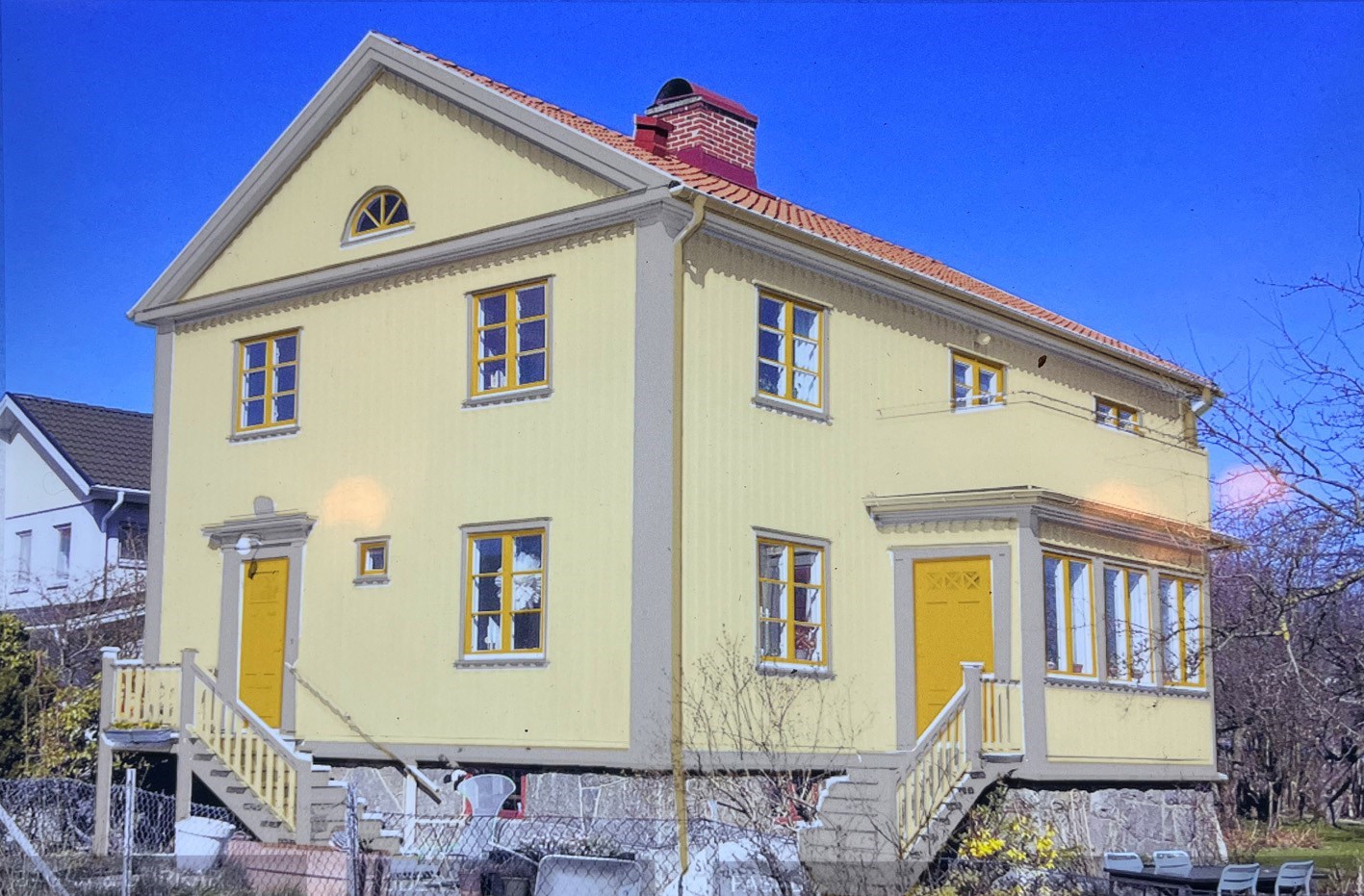 gult hus med grå foder och gula fönster