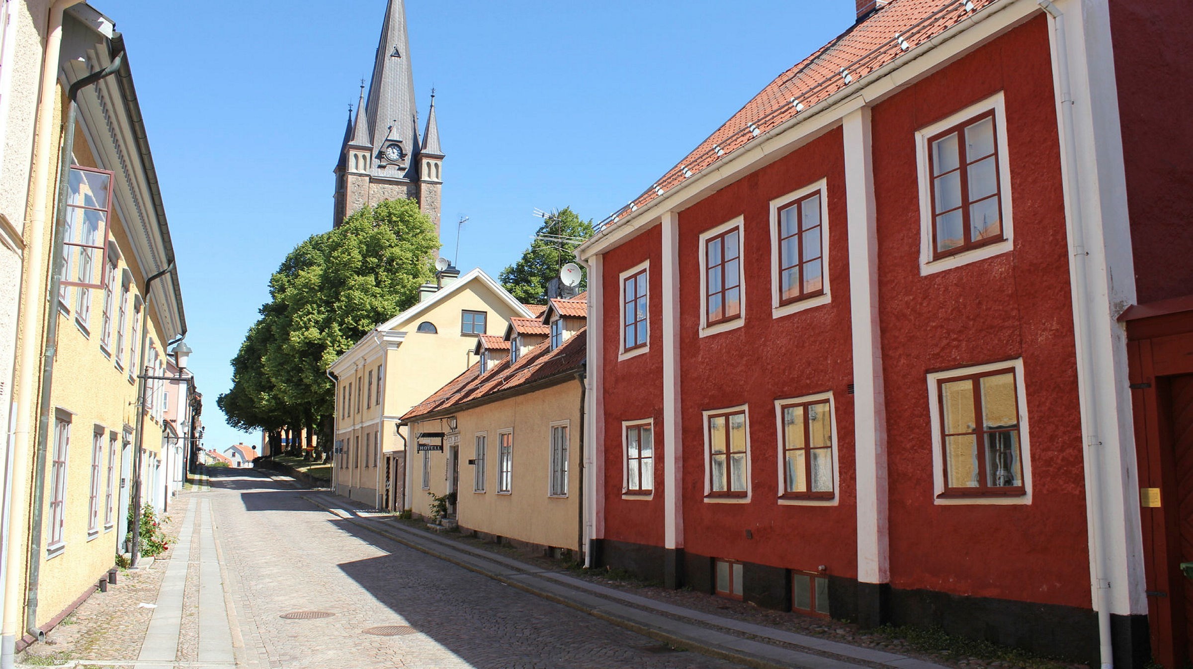 En stadsgata med framför allt gula hus men ett rött med vitmålade knutar ligger kvar